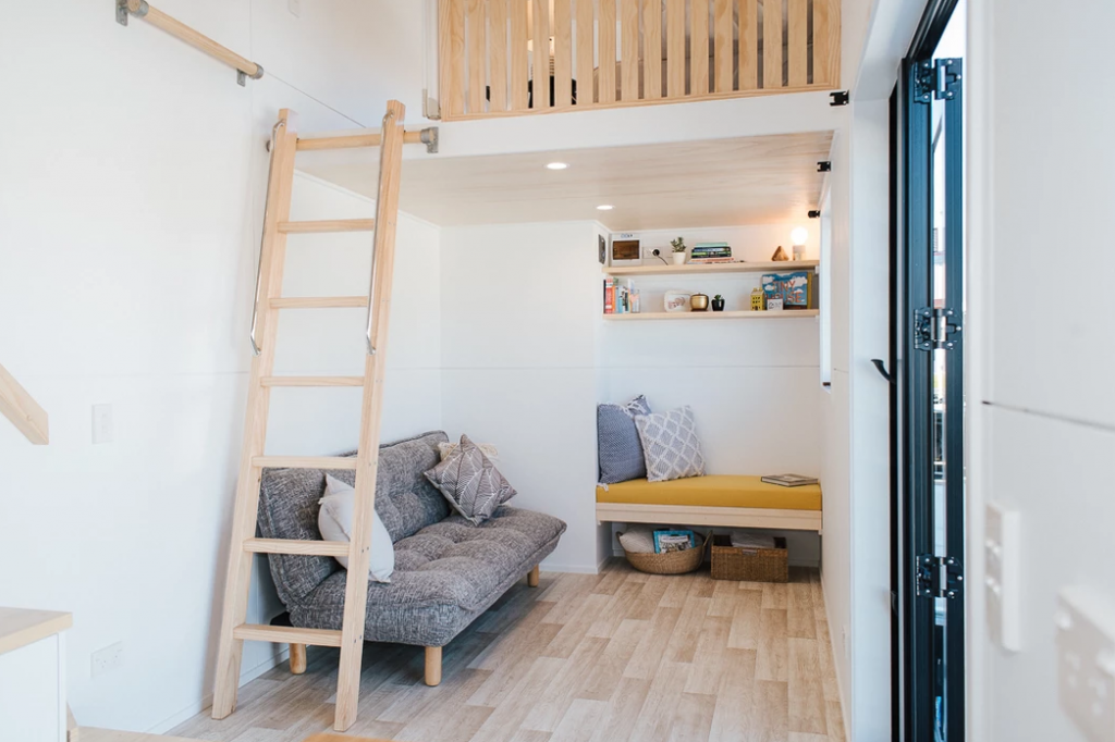 A ladder is used to access the smaller loft area on the left-hand side of the tiny house.