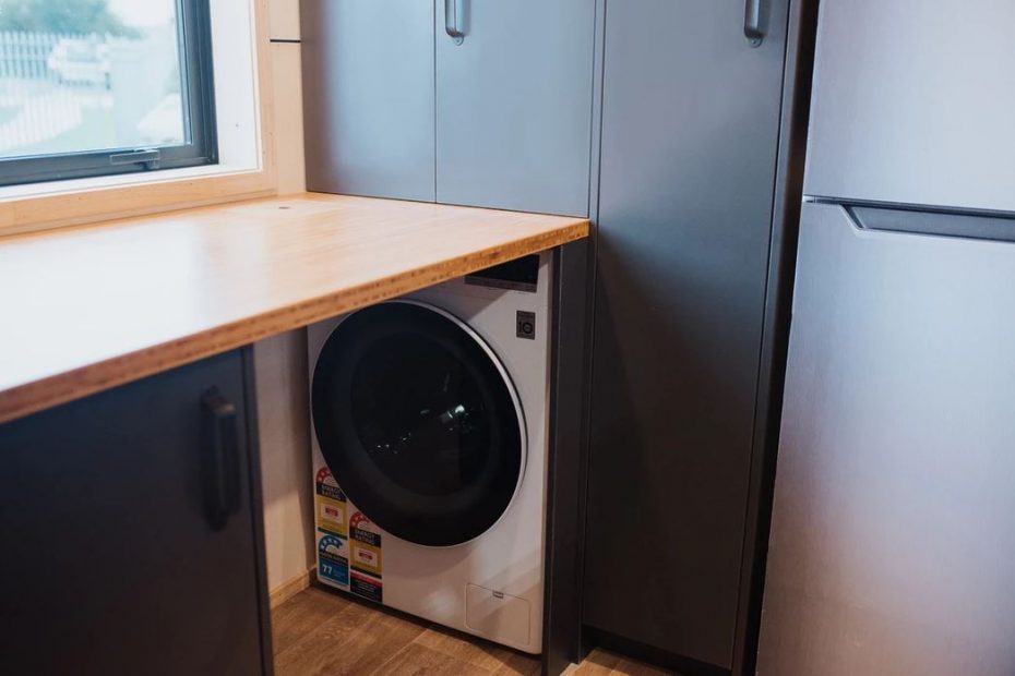 In the River Bank tiny homes, the washing machine is hidden behind a kitchen cabinet that can be moved to allow access to it.
