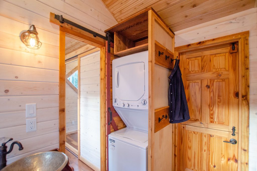 The tiny house laundry room is in the bathroom of the Huckleberry tiny house by Rewild Homes