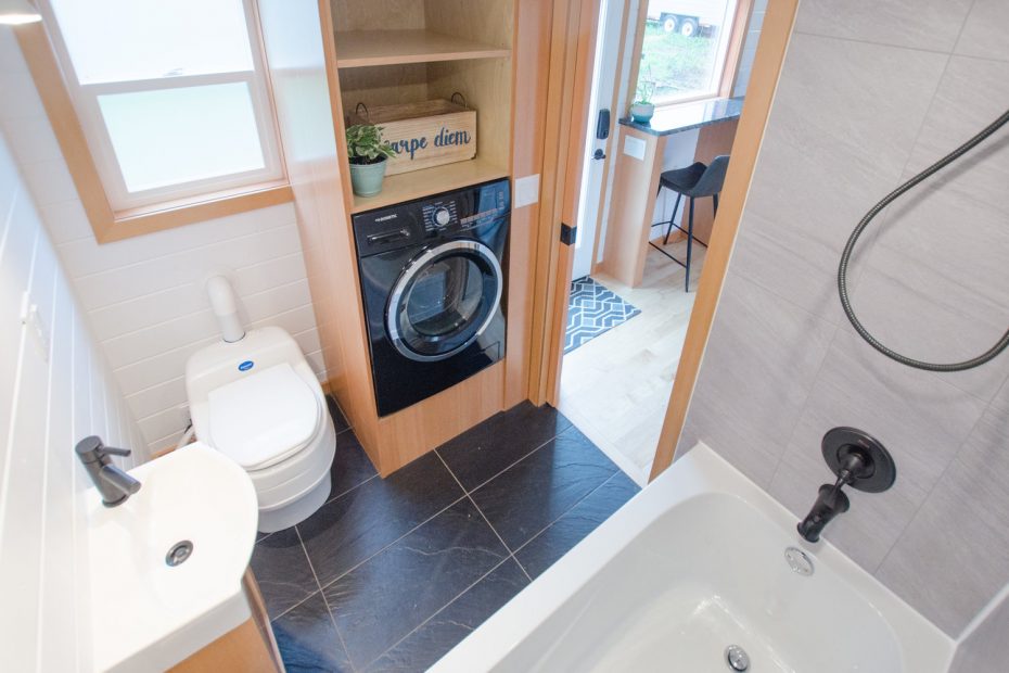 The bathroom in the Albatross tiny house by Rewild homes with a creative washing machine placement.